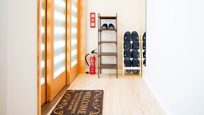 A hallway with a wooden floor, a welcome mat, a fire extinguisher, and shelves with shoes. - Mcity in Furujima (Naha)