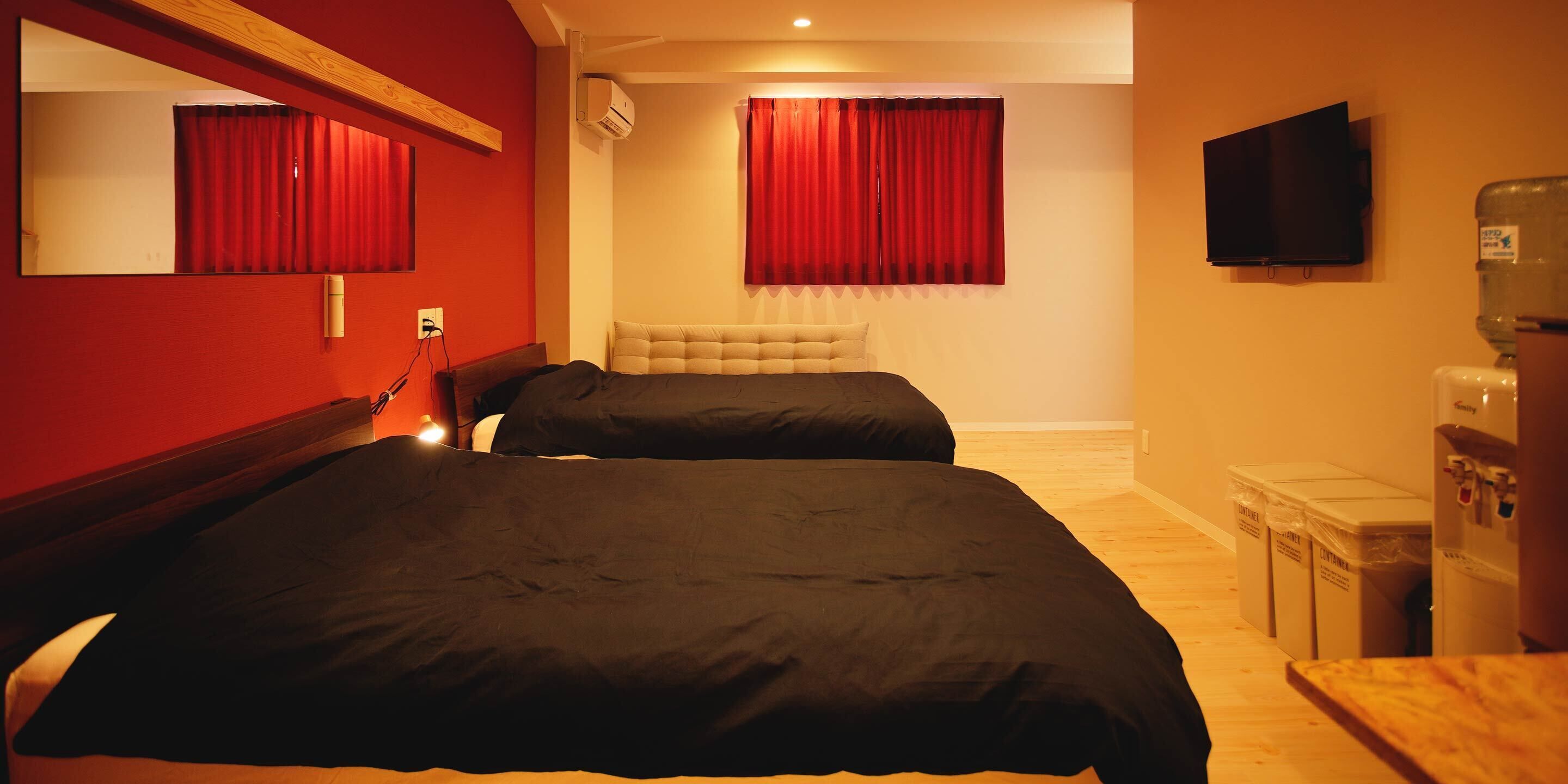 A hotel room with two beds, a large mirror, a flat-screen TV, and a water dispenser.