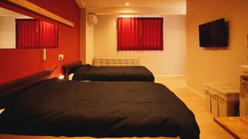 A hotel room with two beds, a large mirror, a flat-screen TV, and a water dispenser.