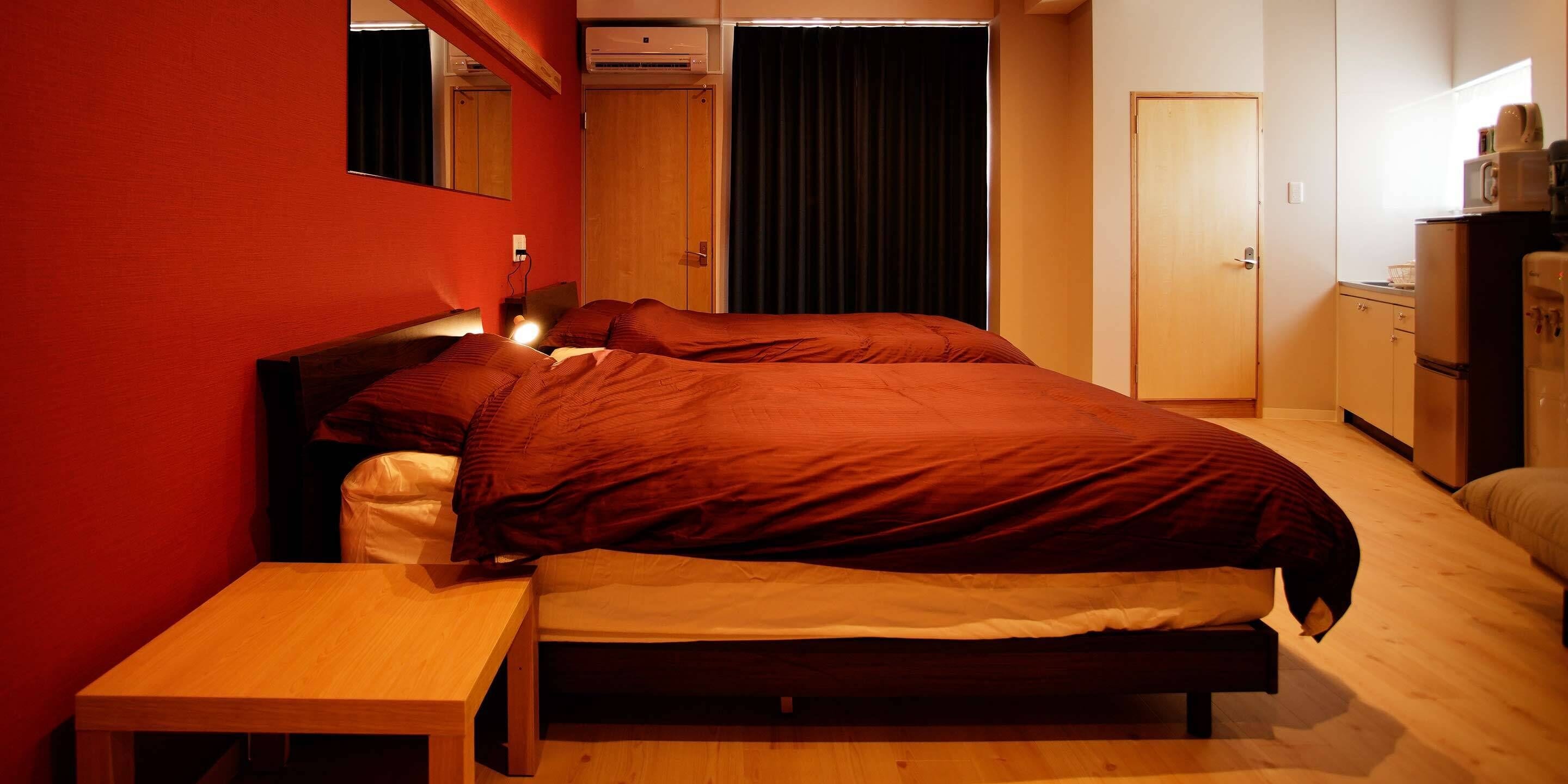 Un dormitorio con cama, mesita de noche, armario y kitchenette.