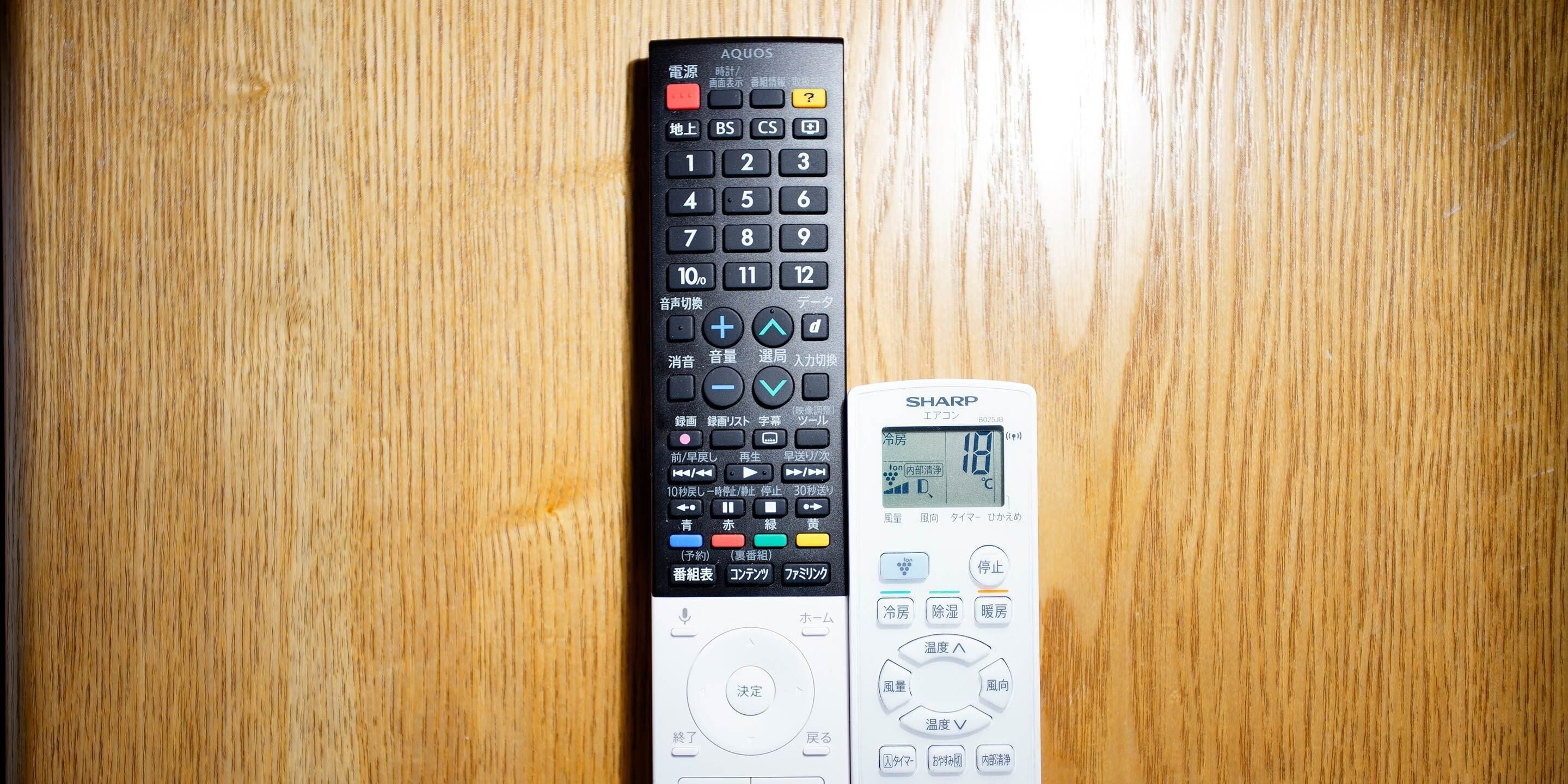 Two remote controls on a wooden surface.