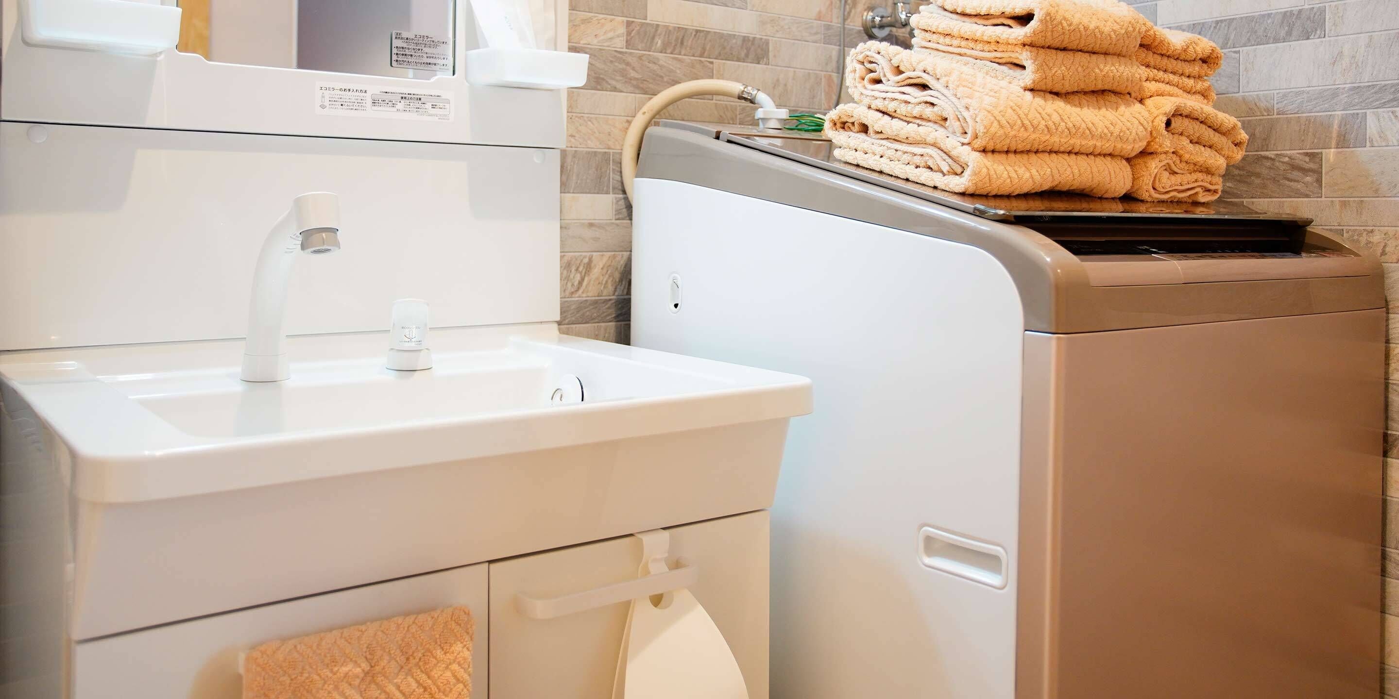 A modern bathroom with a sink, toilet, and stacked towels.