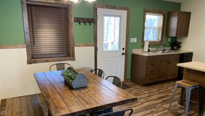 A kitchen with wooden cabinets, a countertop, and a window. - Trailhead Suites (Marysville)