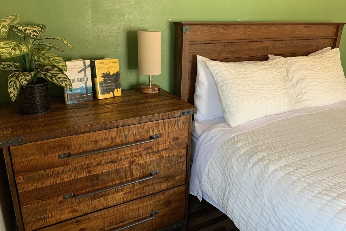 A wooden dresser with drawers, a potted plant, and two books.