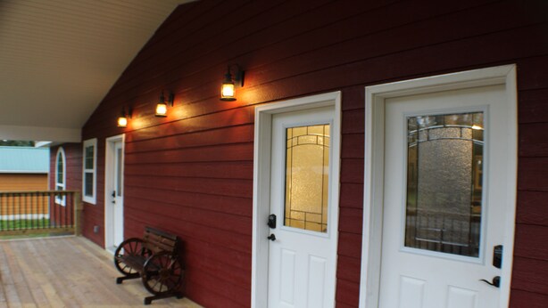A wooden porch with two white doors, each with a glass panel and a small window above. - Trailhead Suites (Marysville)
