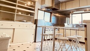 Une cuisine moderne avec des meubles blancs, une hotte en acier inoxydable et un coin repas équipé de tabourets.