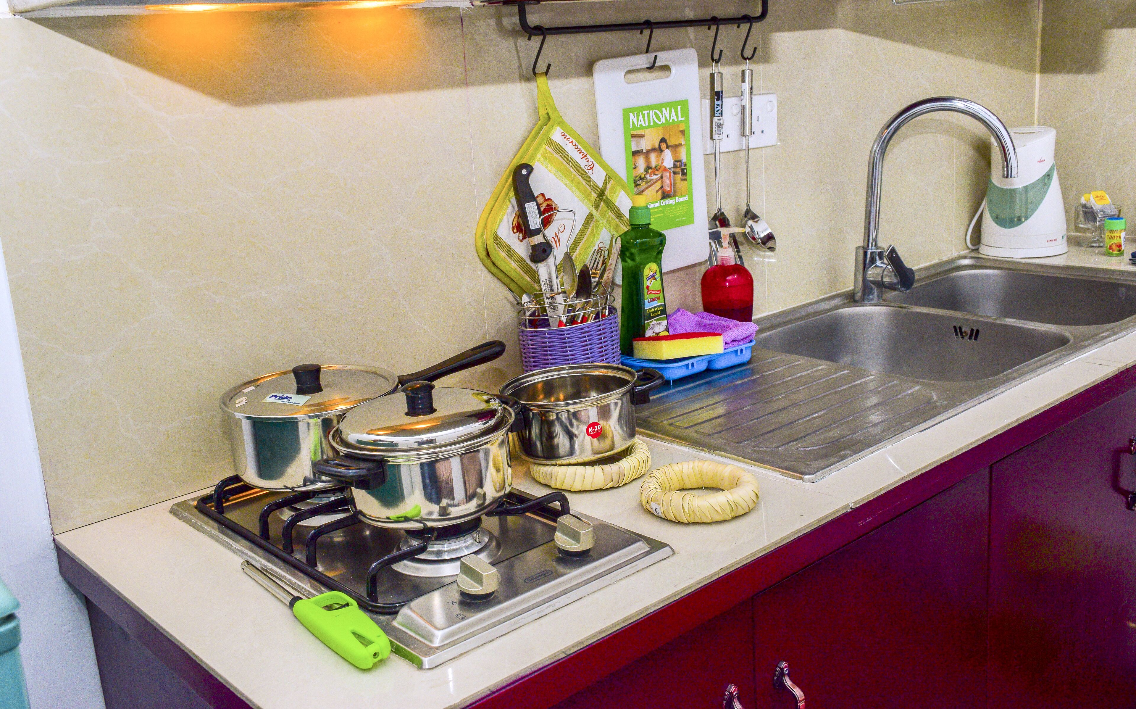 A kitchen with a stove, pots, a kettle, and a sink.