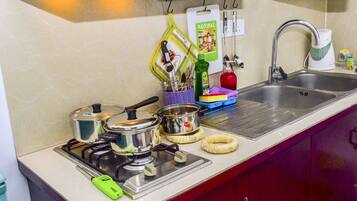 A kitchen with a stove, pots, a kettle, and a sink.