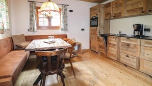 Een gezellige keuken met houten kastjes, een eettafel met stoelen en een raam met gordijnen.
