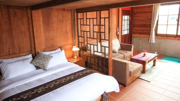 A wooden room with a bed, a chair, a small table, and a window. - Totally Habitat Homestay (Wujie)