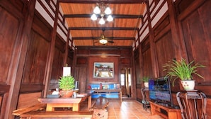A wooden interior with a ceiling fan, a television, and potted plants. - Totally Habitat Homestay (Wujie)