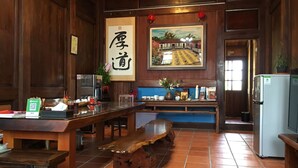 A traditional wooden interior with a long table, a bench, and a refrigerator. - Totally Habitat Homestay (Wujie)