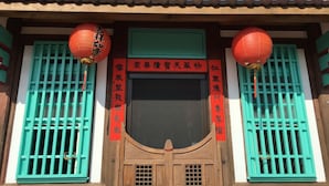 A traditional building with a wooden door and green window shutters. There are red lanterns hanging above the door. - Totally Habitat Homestay (Wujie)