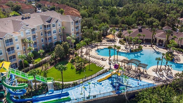 A resort with a large pool, water slides, and a building with multiple balconies. - Steps from clubhouse.  "Be Our Guest" in Windsor Hills-pool heat included (Kissimmee)