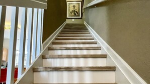 A staircase with wooden steps and white railings, leading to a landing with a framed picture. - Steps from clubhouse.  "Be Our Guest" in Windsor Hills-pool heat included (Kissimmee)