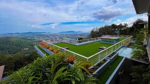 A rooftop garden with a panoramic view of a cityscape and mountains. - Phuket View Coffee and Resort (Chalong)