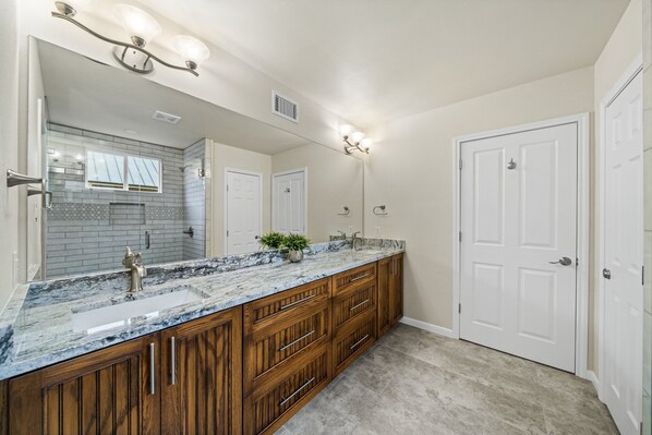 A bathroom with a large vanity, a mirror, and a shower.