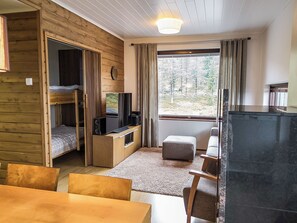 A compact room with a bunk bed, a television, a small table, and a window with curtains. - Villa ylläs 302 by Interhome (Ylläsjärvi)