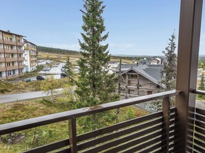 A balcony with a view of a parking lot, a building, and a forested area. - Villa ylläs 302 by Interhome (Ylläsjärvi)