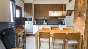Una cocina compacta con armarios de madera, una mesa de comedor con sillas y un refrigerador.