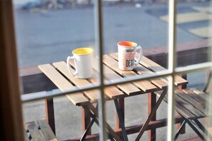 Two white mugs with yellow and orange designs on a wooden table through a window. - Brothers Pension (Sokcho)