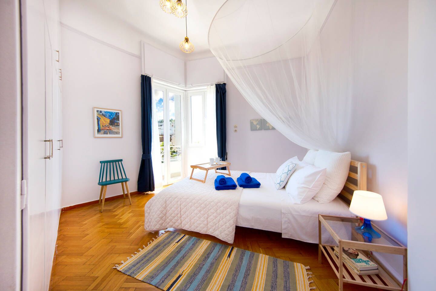 A bedroom with a bed, a bedside table, a chair, a window with curtains, and a view of the outdoors.