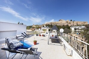 A rooftop terrace with a bed, lounge chairs, and potted plants. - Your Home under the Acropolis Roofdeck (Athens)