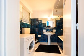 A compact bathroom with a washing machine, a sink, and a toilet. - Your Home under the Acropolis Roofdeck (Athens)