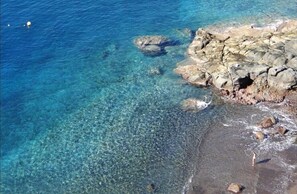 Experience the tranquility of a secluded coastal haven with clear waters and rugged shoreline.