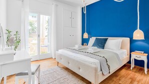 A bedroom with a bed, bedside tables, a desk, and a window.