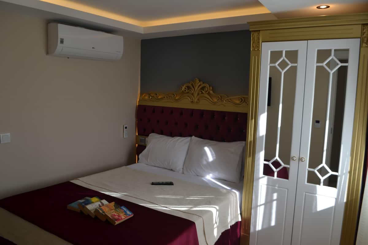 Une chambre d’hôtel avec un lit, une télécommande et une pile de livres posée sur le lit.