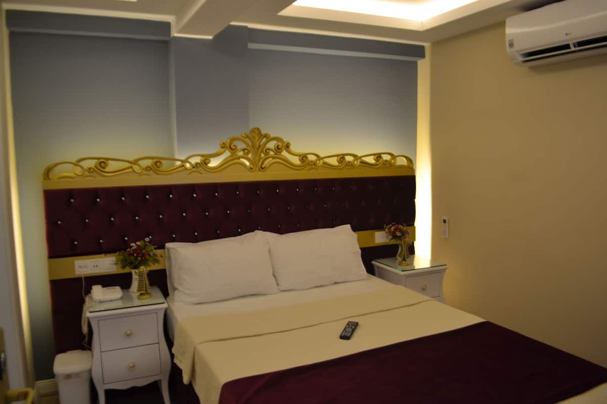 Une chambre d’hôtel avec un grand lit, une table de chevet et un climatiseur.