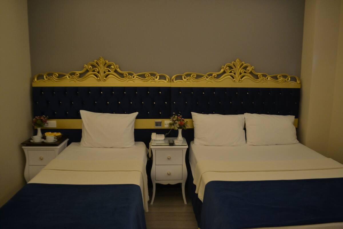 Une chambre d’hôtel avec deux lits, une tête de lit bleu foncé et un élément décoratif jaune.