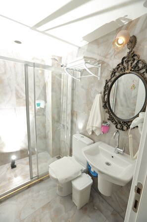 A modern bathroom with a glass shower enclosure, a white sink, and a large mirror with an ornate frame. - Constantinopolis Hotel (Istanbul)