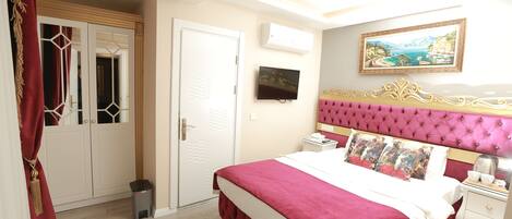 A bedroom with a large bed, a television, a painting, and a wardrobe.