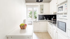 Una cucina moderna con mobili bianchi, forno integrato e microonde.