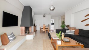 Un soggiorno moderno con camino, televisione a schermo piatto, divano e zona pranzo.