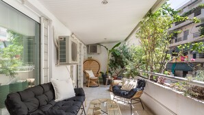 Un balcone con un divano nero, poltrone in vimini e un tavolo in vetro.