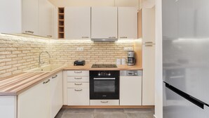 A modern kitchen with white cabinets, a brick backsplash, a stainless steel refrigerator, and a Bosch oven. - Serene Acropolis View Roofdeck (Athens)