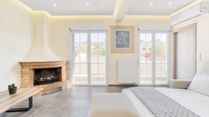 A spacious bedroom with a large bed, a fireplace, and a view through the glass doors. - Serene Acropolis View Roofdeck (Athens)