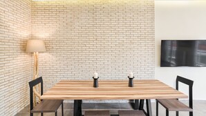 A dining area with a wooden table, black chairs, and a brick wall. - Serene Acropolis View Roofdeck (Athens)
