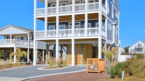 A multi-story beachfront hotel with balconies, a covered entrance, and a sandy driveway. - Anita Getaway: Charming 4-bedroom home in Oak Island with ocean views and private pool. (Oak Island)