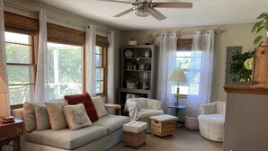 A cozy living room with a sofa, armchairs, a small table, and a bookshelf. - Chickadees Cottage and Pottery - centrally located, private comfortable cottage. (Arden)