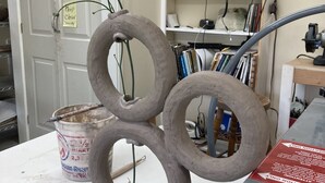A sculpture of interconnected rings on a workbench in a room with a door, shelves with books, and a computer monitor. - Chickadees Cottage and Pottery - centrally located, private comfortable cottage. (Arden)