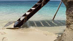 A staircase leading to a beach with clear turquoise water and a rocky outcrop. - Gadea Boutique Hotel (Jambiani)