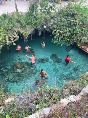 A group of people in a natural pool surrounded by greenery and rocks. - Gadea Boutique Hotel (Jambiani)