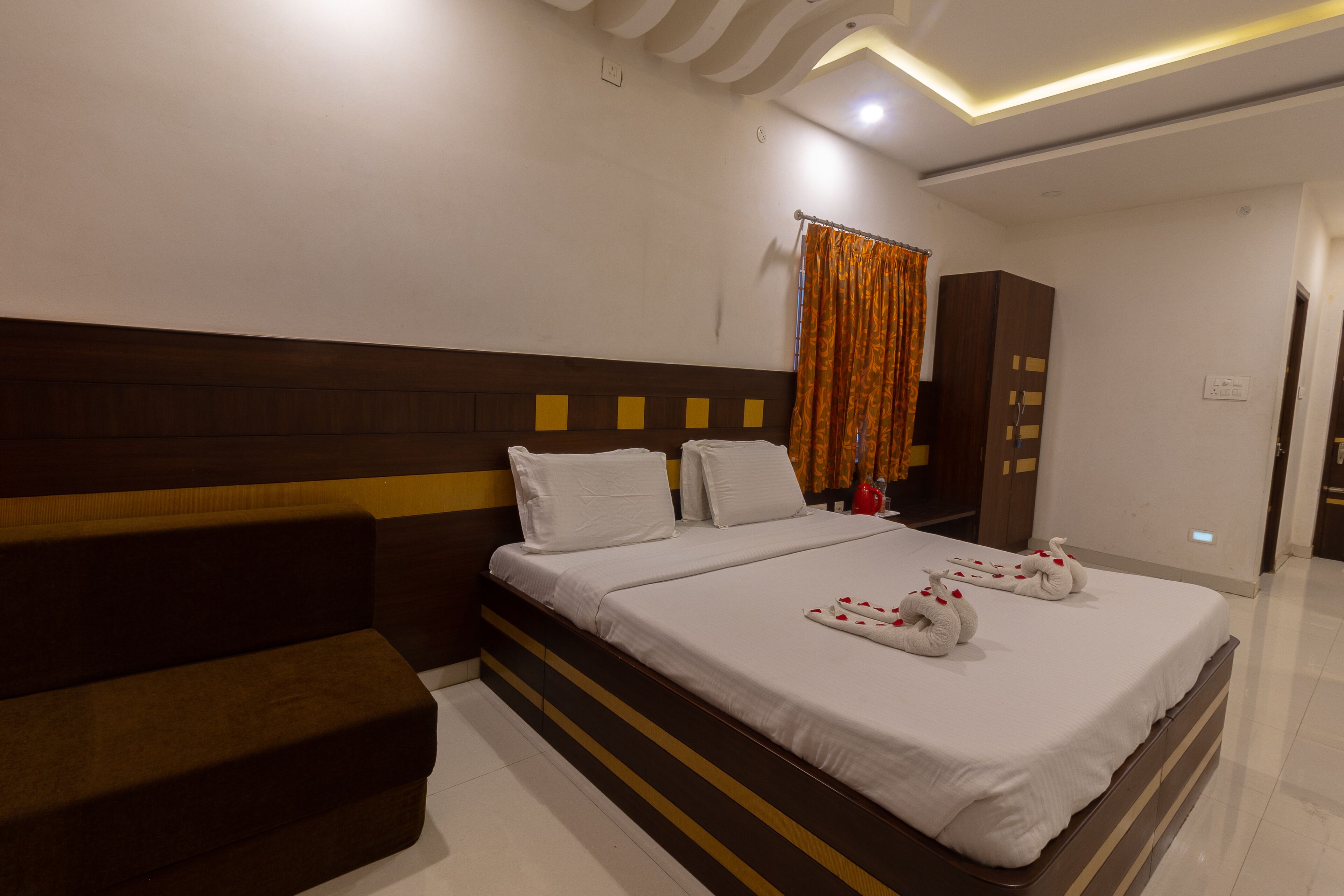 Habitación de hotel con una cama grande, cabecero de madera, un banco y un armario.