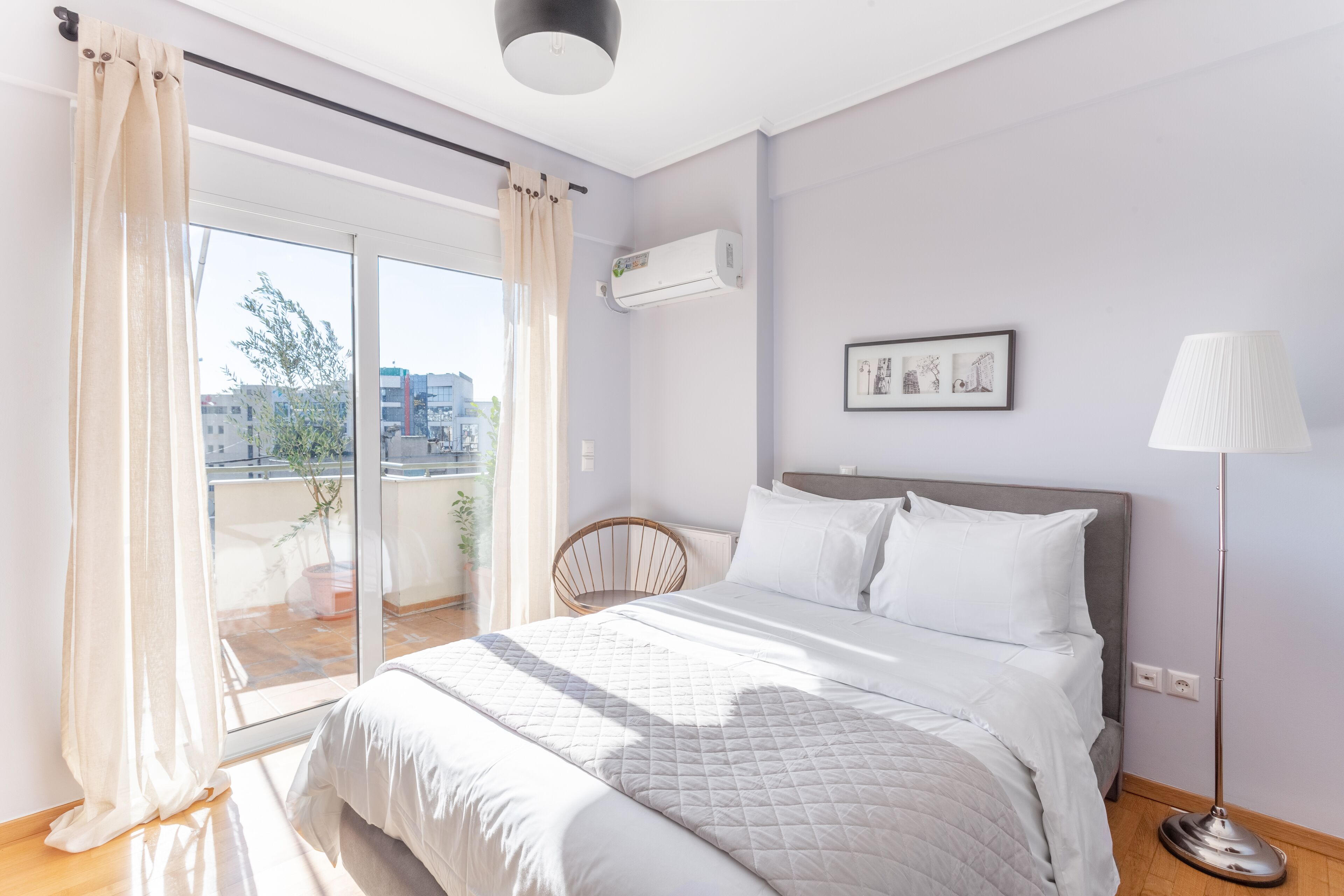 Een slaapkamer met een bed, een stoel, een vloerlamp en een raam met gordijnen.