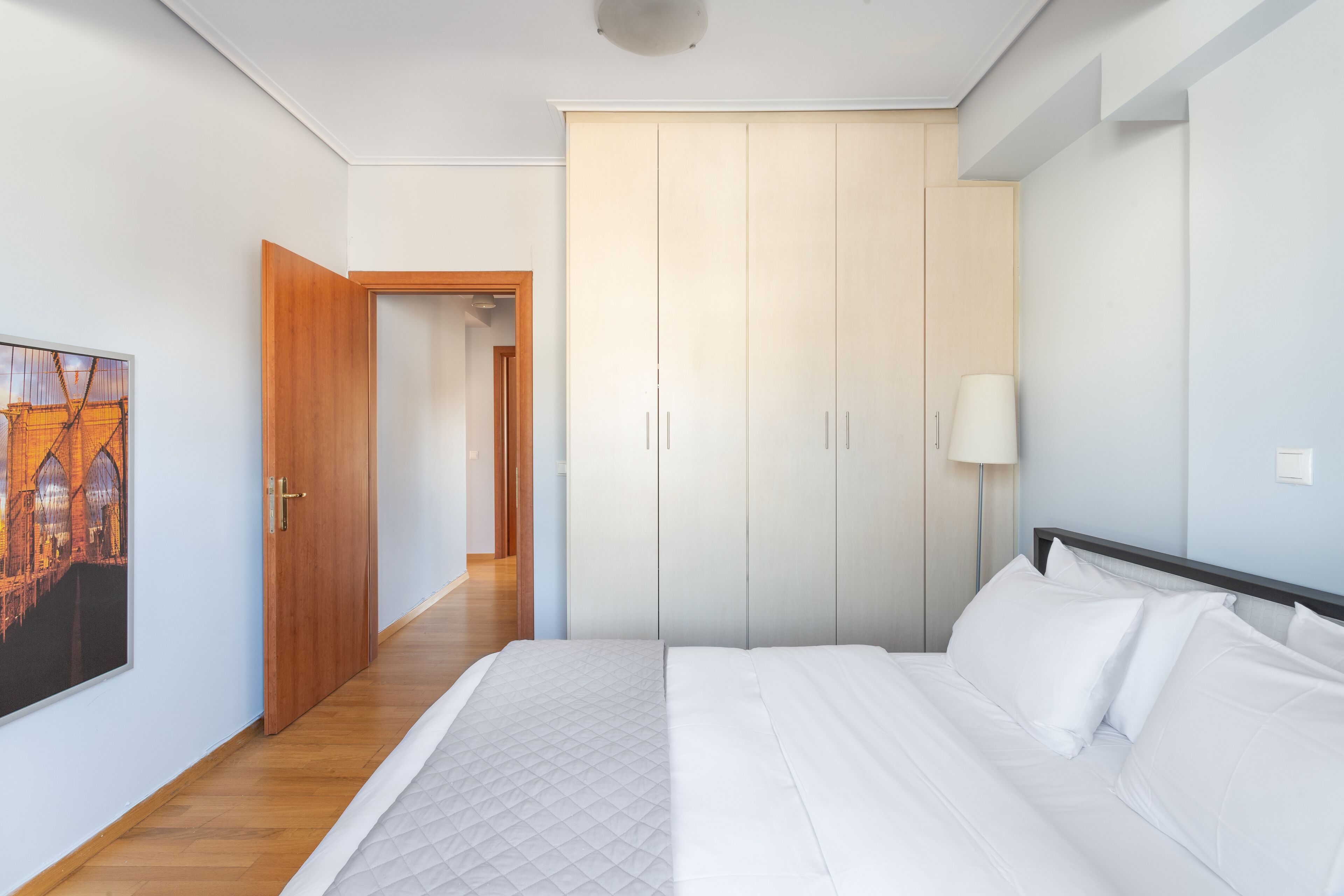 Une chambre à coucher avec un lit, une armoire, un tableau et une lampe.