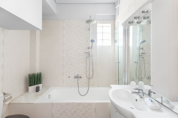 A modern bathroom with a bathtub, shower, and sink.
